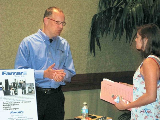 Doug Schmidt, left, engineering manager for Farrar Scientific, speaks with Parkersburg resident Eva Frey, right, during Wednesday's The Parkersburg News and Sentinel Job Fair at the Grand Pointe Conference Center in Vienna.  The event helps employers quickly find applicants while giving job seekers a wide range of jobs from which to choose. (Photo by Michael Erb)