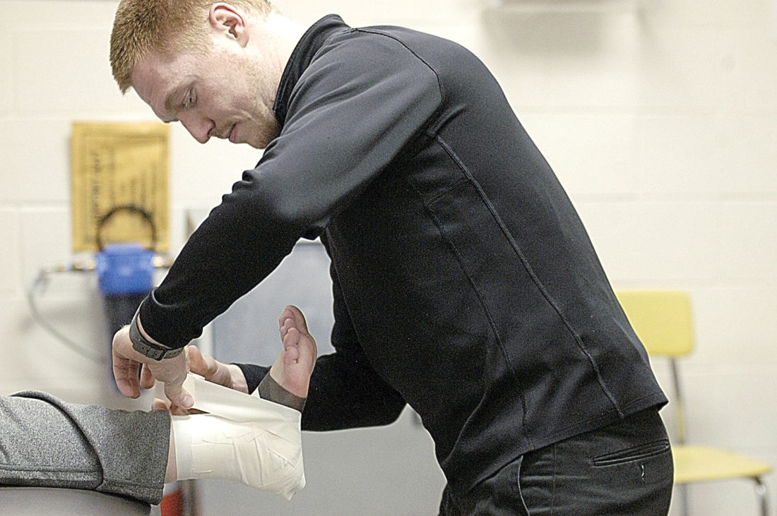 Staff photo by Jake ATC Scott Mangen tapes an ankle in the athletic training room at New Ulm High School. Mangen is one of four full-time athletic trainers contracted through the Courage Kenny Rehab Institute at the New Ulm Medical Center.