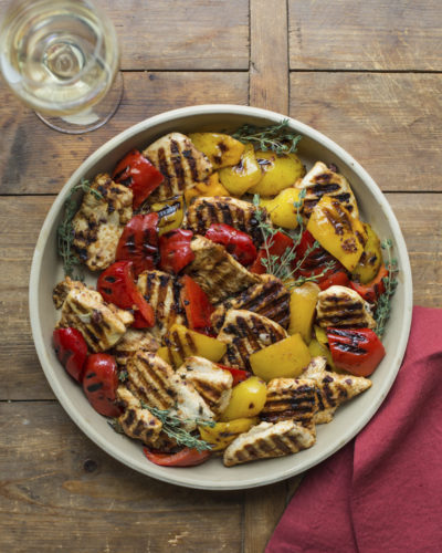 This April 2017 photo shows grilled lemony chicken and peppers in New York. This dish is from a recipe by Katie Workman. (Sarah Crowder via AP)