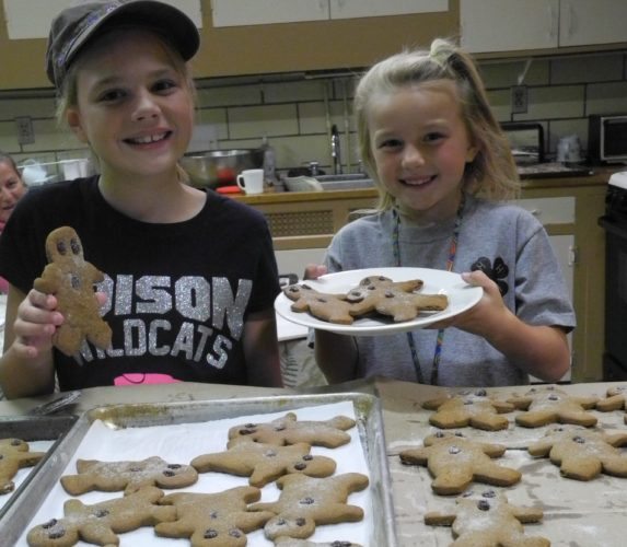 The best part of helping to make gingerbread boy cookies for the Unionport Apple Stirrin' cookie cabin is tasting one. Olivia Ault, 9, left, and her sister, Amelia, 7, give a big smile of approval for the huge gingerbread boys that are coated with crystal sugar and decorated with raisin eyes and buttons. It was told that the recipe is more than 100 years old and from the kitchen of Grandma Peterson, a deceased relative of some of the festival and Unionport Grange members. -- Esther McCoy